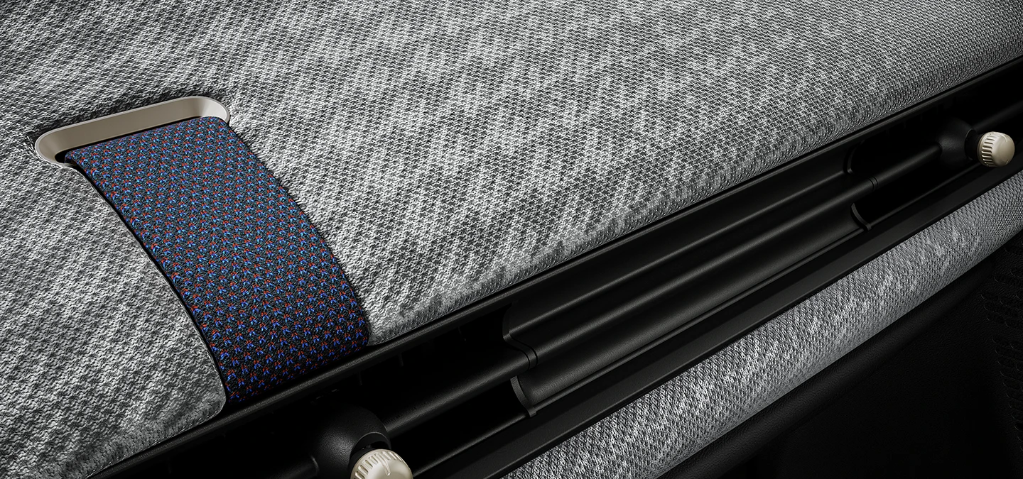 Bližnji pogled na armaturno ploščo iz 2D-prediva v notranjosti MINI Cooper.