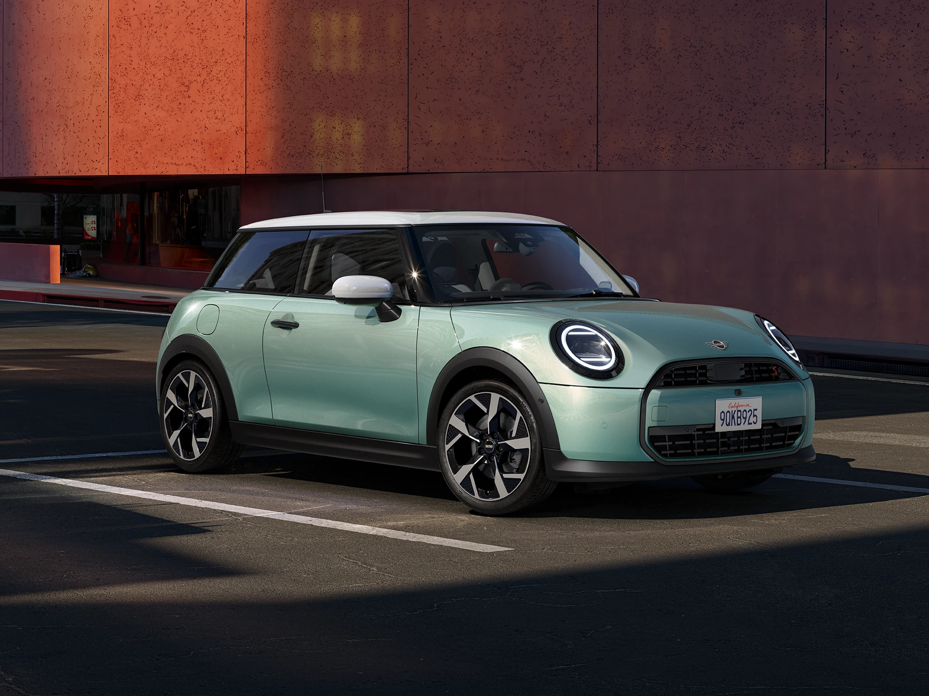 Stranski pogled od spredaj na MINI Cooper v barvi Ocean Wave Green s streho v beli barvi.