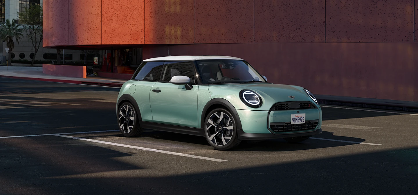 Stranski pogled od spredaj na MINI Cooper v barvi Ocean Wave Green s streho v beli barvi.