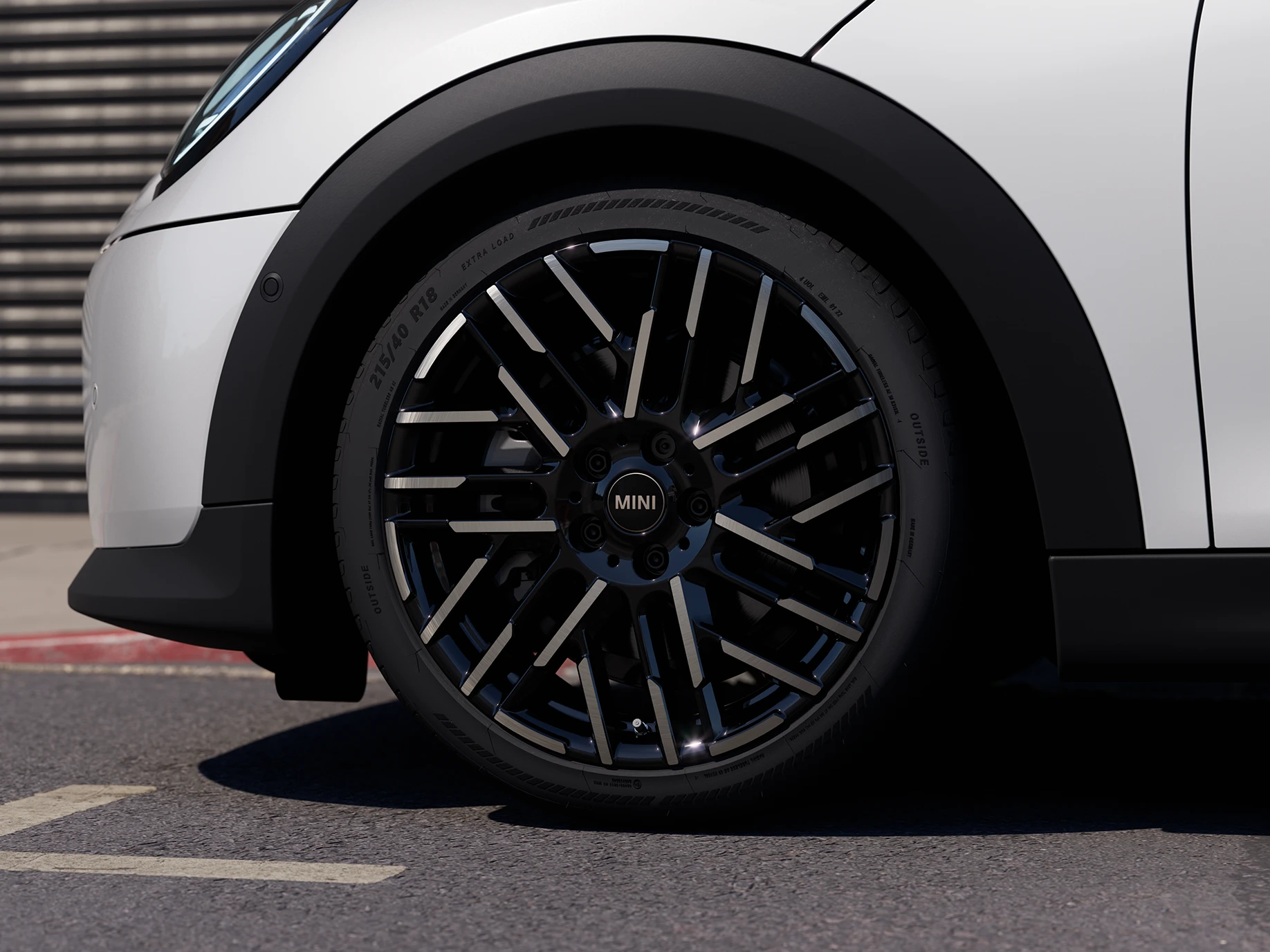 Bližnji posnetek MINI Cooper s petimi vrati v barvi Nanuq White z dvobarvnimi platišči Night Flash Spoke.