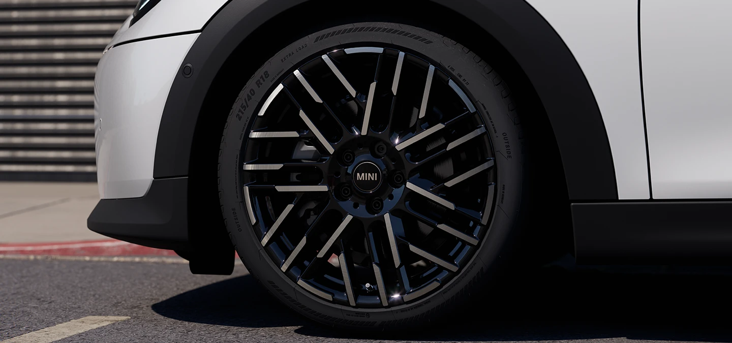 Bližnji posnetek MINI Cooper s petimi vrati v barvi Nanuq White z dvobarvnimi platišči Night Flash Spoke.