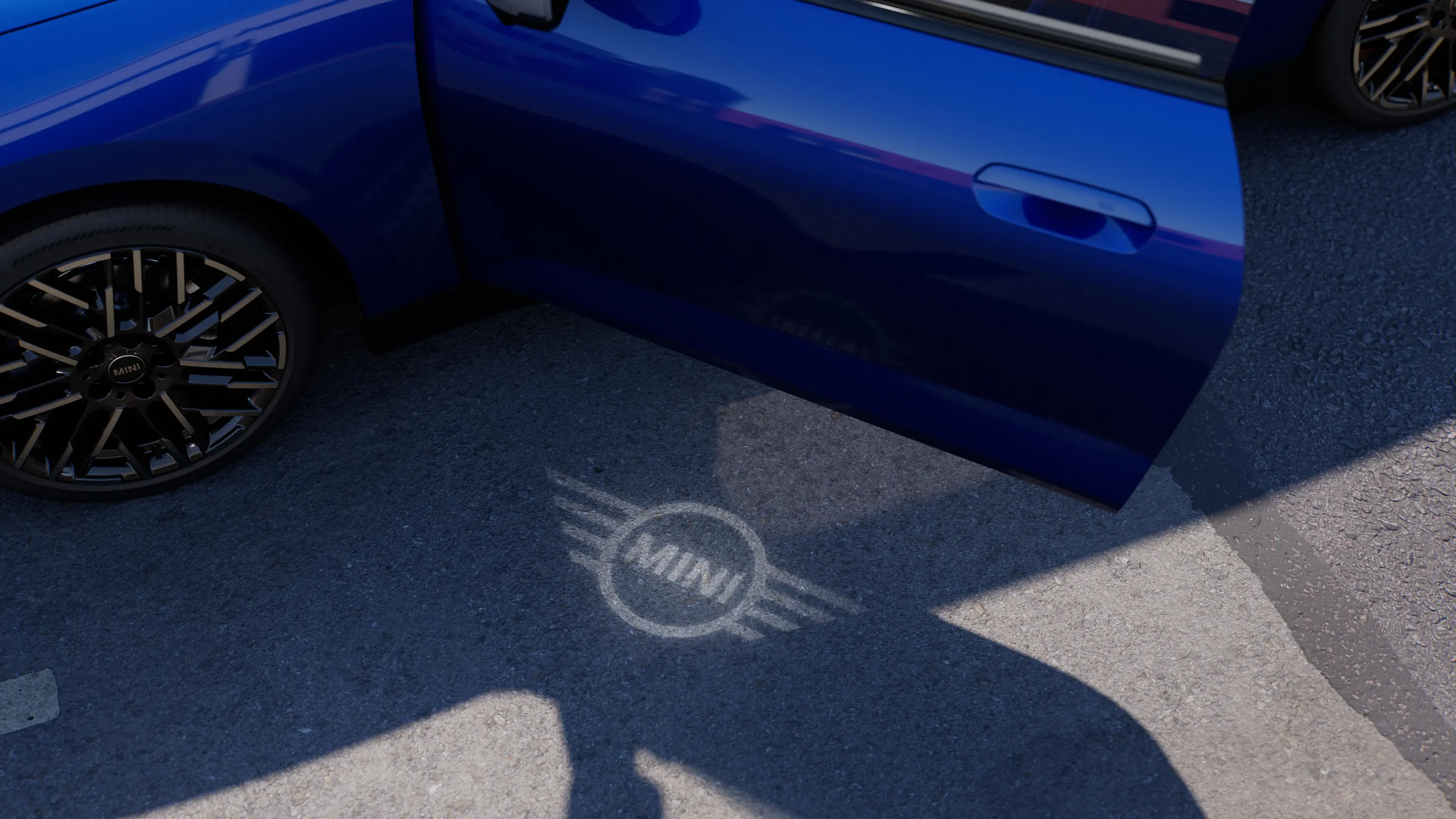 Pogled na zunanjost popolnoma električnega MINI Cooper z odprtimi vrati in lučjo dobrodošlice z logotipom MINI na tleh