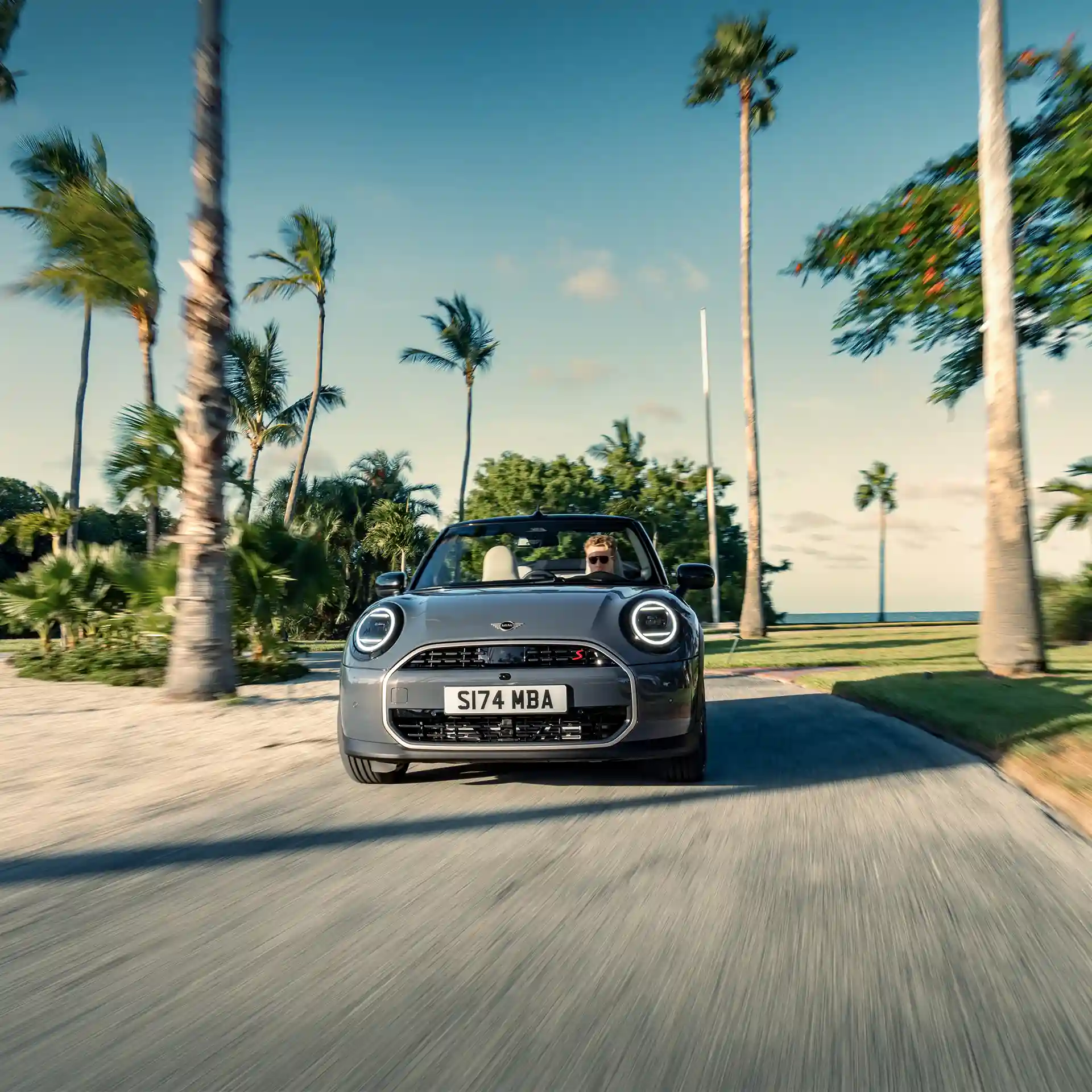 Pogled od spredaj na MINI Cooper Cabrio v barvi Copper Grey med vožnjo po ulici