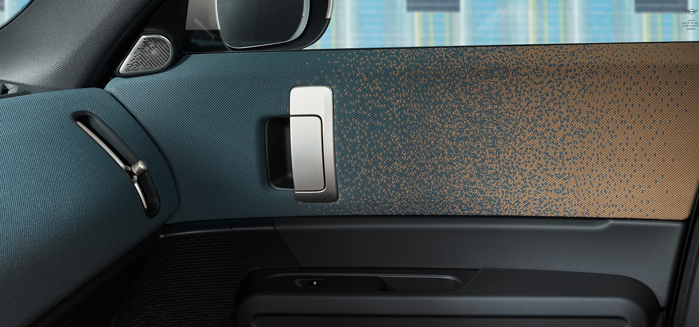 Bližnji pogled na notranjo zasnovo električnega MINI Countryman s poudarkom na vratih in armaturni plošči.