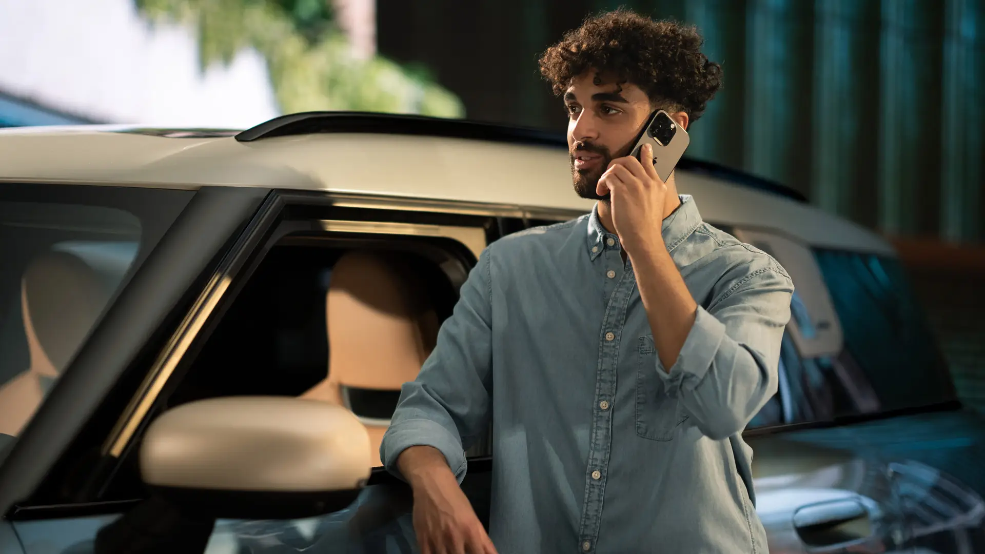 Proaktivna skrb MINI – moški stoji ob svojem vozilu MINI in se po telefonu pogovarja s servisnim svetovalcem.