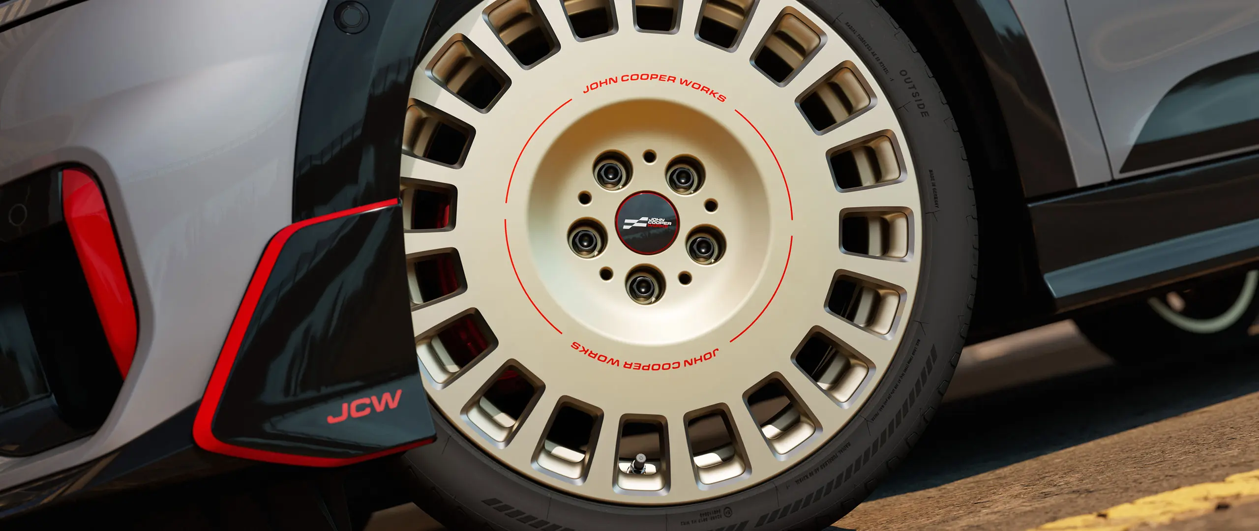 Bližnji posnetek 18-palčnega kolesa JCW Rallye Spoke 964 v dvobarvni kombinaciji Vibrant Silver z diamantno obdelavo in sprednjim zakrilcem.