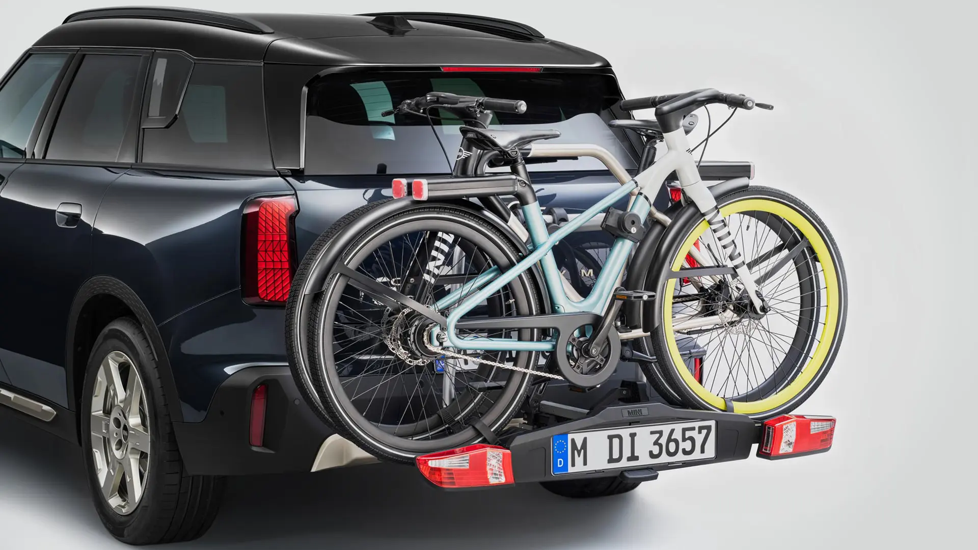MINI Countryman v črni barvi z zadnjim nosilcem za kolesa in dvema pritrjenima gorskima kolesoma, pogled od zadaj