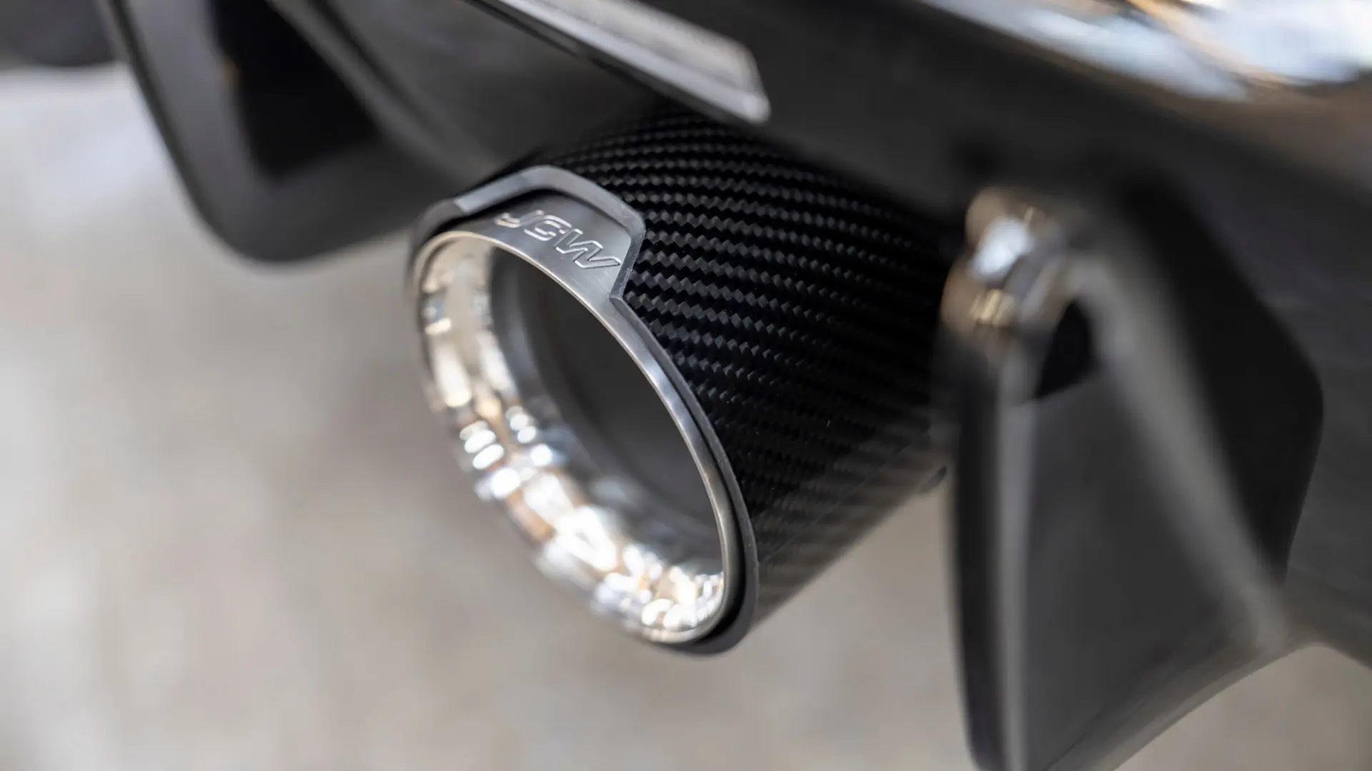 Okrasni nastavek za izpušno cev MINI John Cooper Works se lahko pritrdi na izpušni sistem in vozilu doda dirkaški videz. 