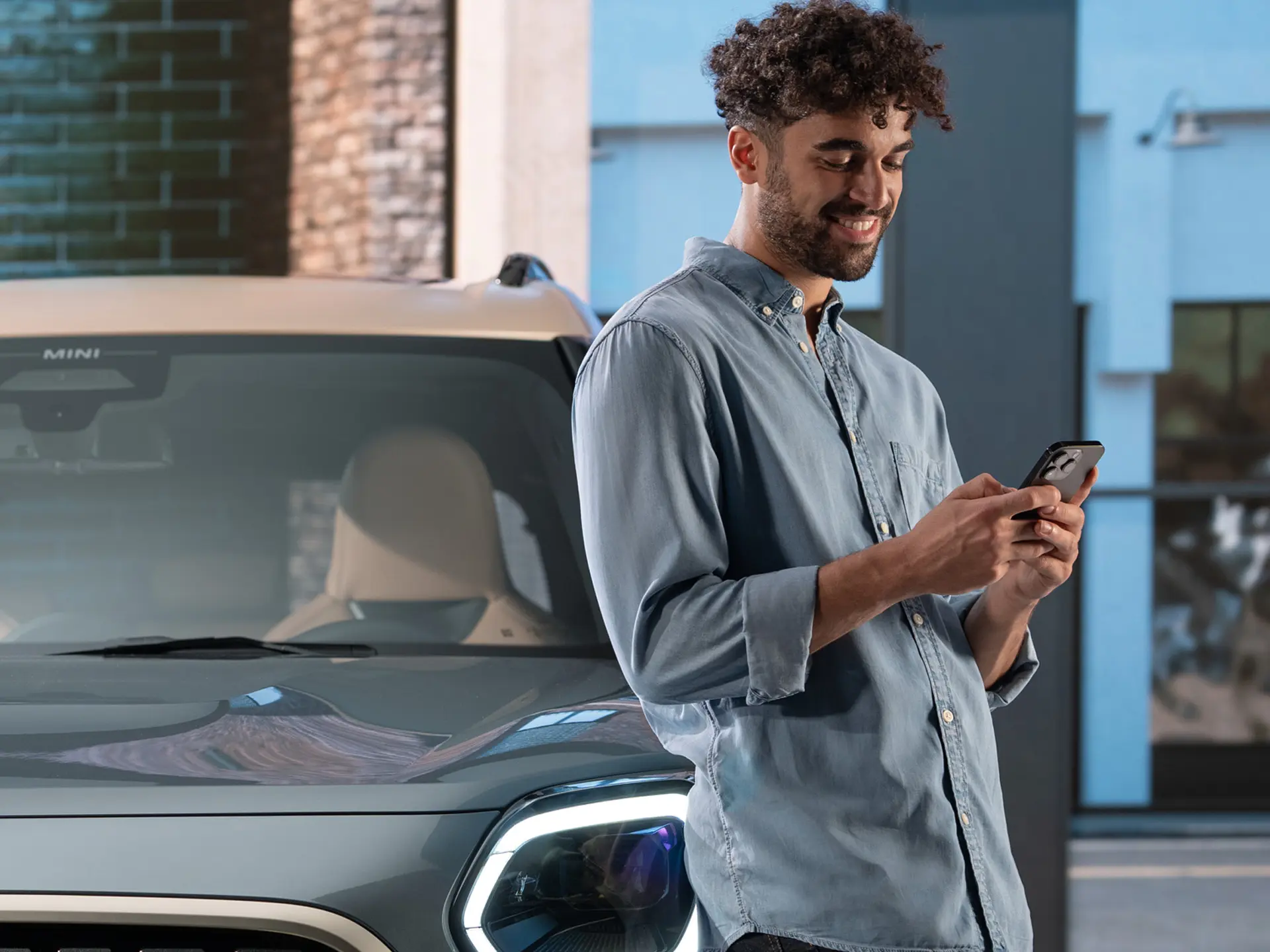 MINI personalizirani servisni termini - moški, ki tipka na telefon poleg MINI