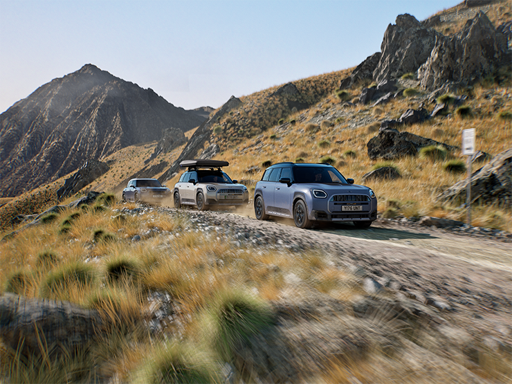 Slika več vozil MINI Countryman Untamed Edition med terensko vožnjo po gorski cesti.