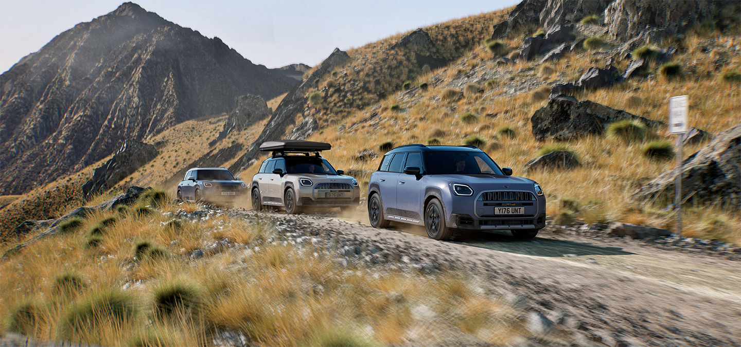 Slika več vozil MINI Countryman Untamed Edition med terensko vožnjo po gorski cesti.