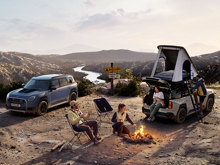 Slika dveh vozil MINI Countryman Untamed Edition na gori ob sončnem zahodu.