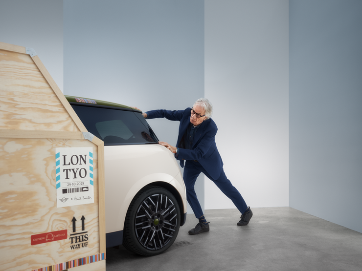 Pogled od zadaj na MINI Cooper Paul Smith Edition v barvi Inspired White, s Paulom Smithom za vozilom