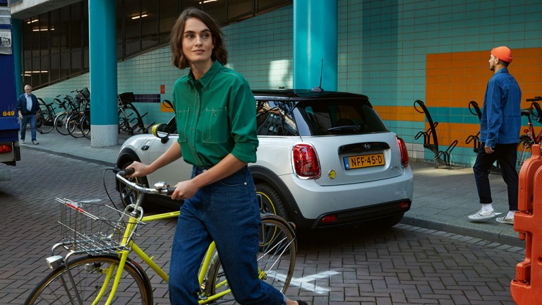 Woman with a bike in front of MINI Electric