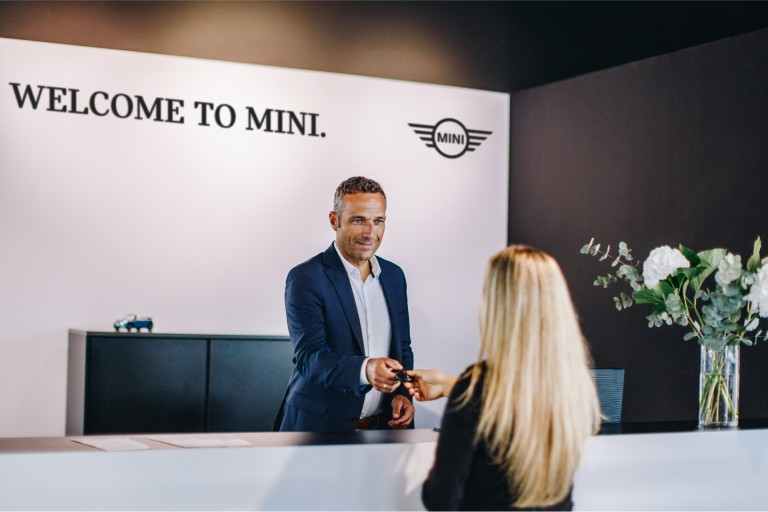 Sprejemni pult v prodajnem salonu MINI z zaposlenim in stranko